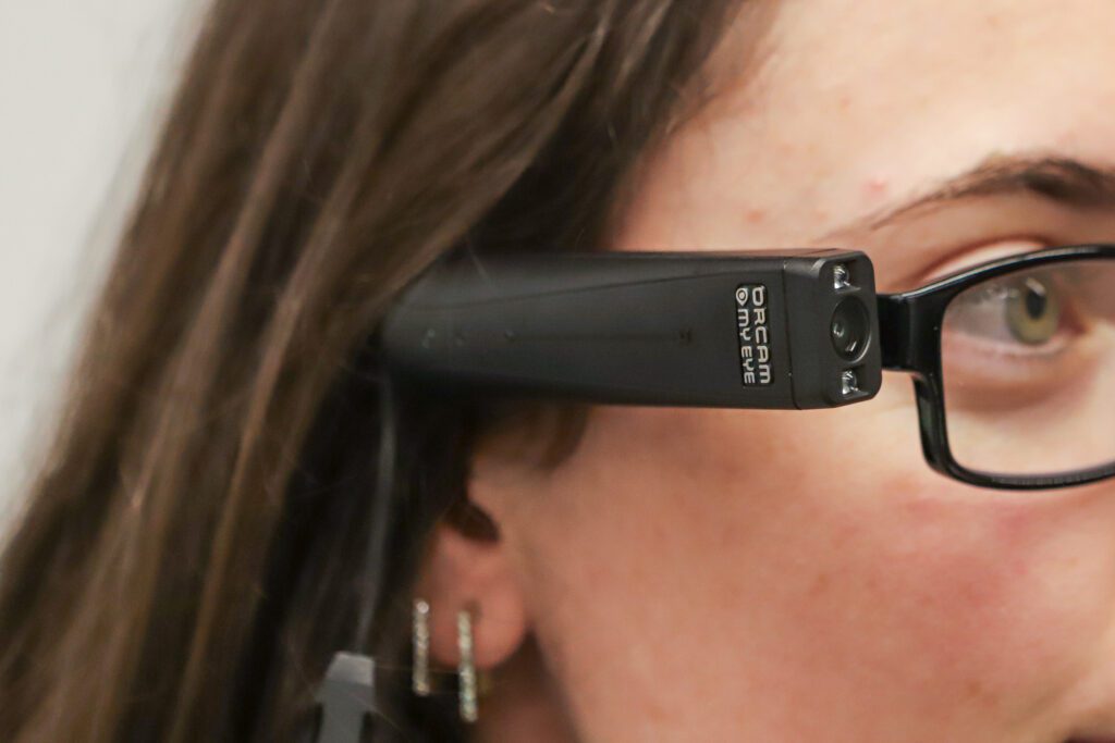 Close-up da parte lateral da cabeça de uma mulher, mostrando a câmera da haste do óculos falante, Orcam. (Crédito AEN)