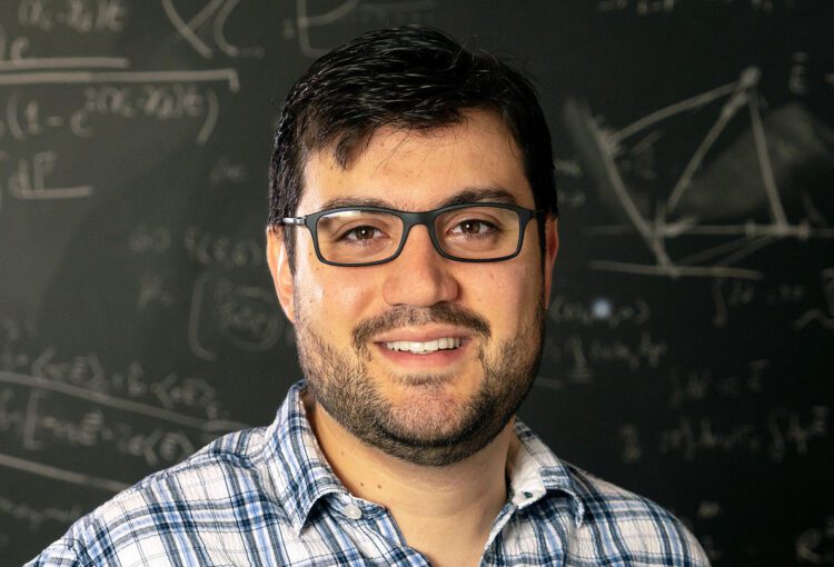 O físico brasileiro Vinícius Njaim Duarte, pesquisador do Laboratório de Física de Plasmas de Princeton (PPPL), da Universidade de Princeton. Homem branco, moreno de óculos em frente a um quadro-negro.